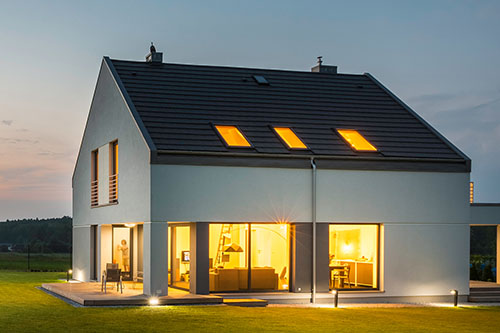 Panoramic photo of modern house with outdoor and indoor lighting, at night